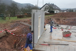 A concrete wall is set on the concrete base of the house
