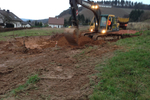 A digger digging soil on a plot of land
